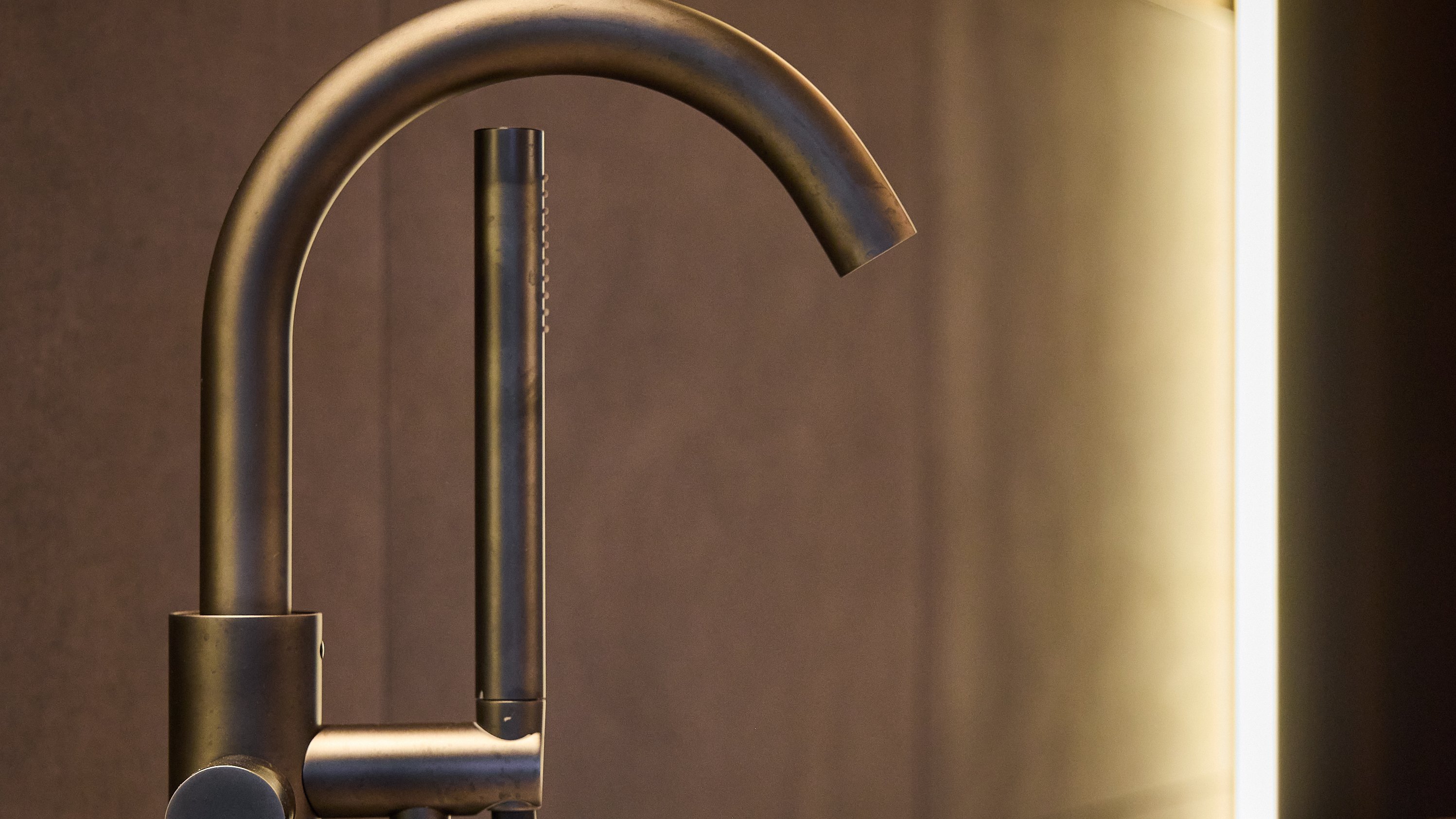 Detailaufnahme eines modernen Badezimmerwasserhahns neben einer weißen Badewanne