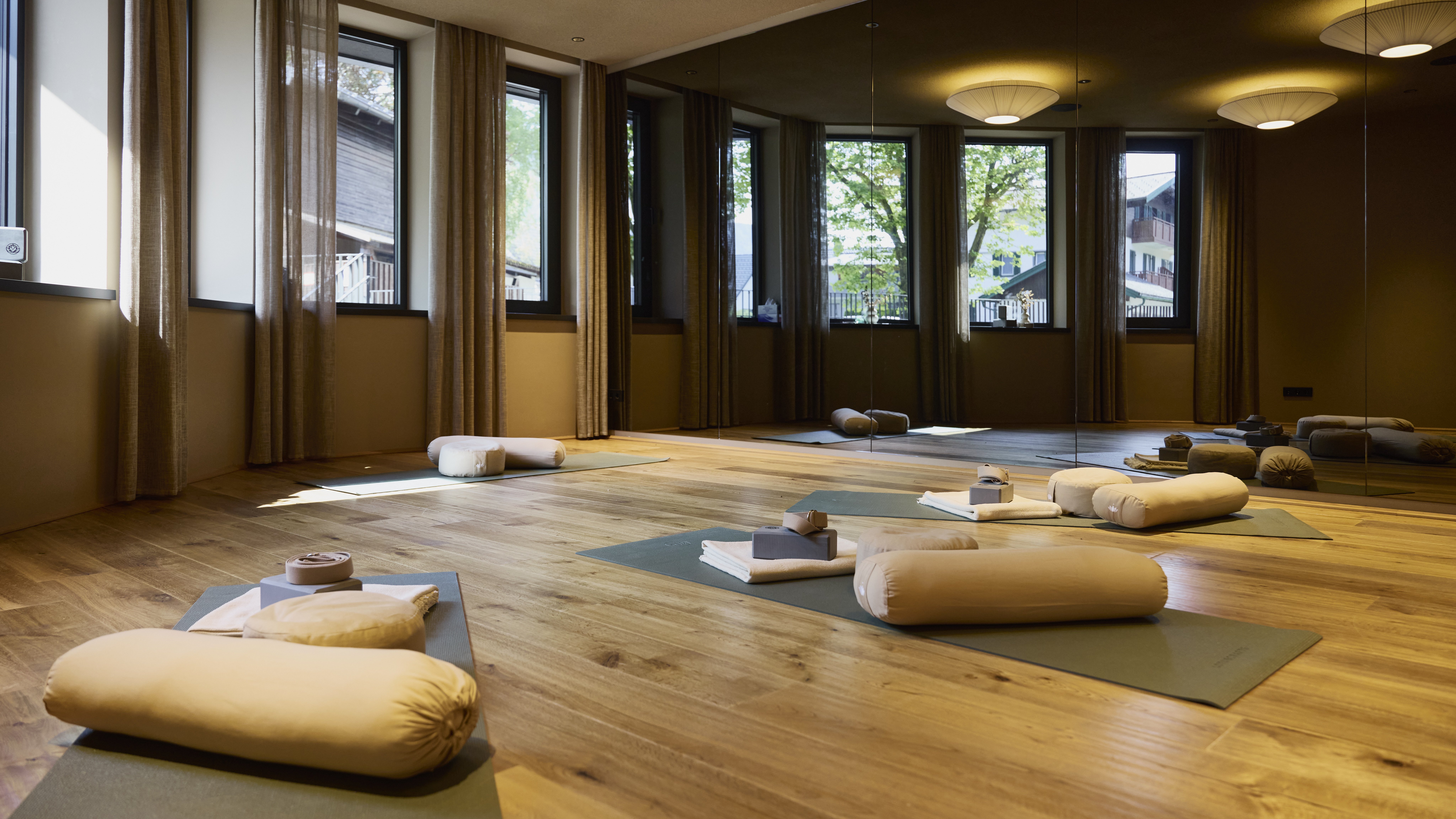 Yoga Raum für innere Ruhe Yoga Studio mit Holzfußboden, Matten und Kissen in hellem Raum mit großen Fenstern