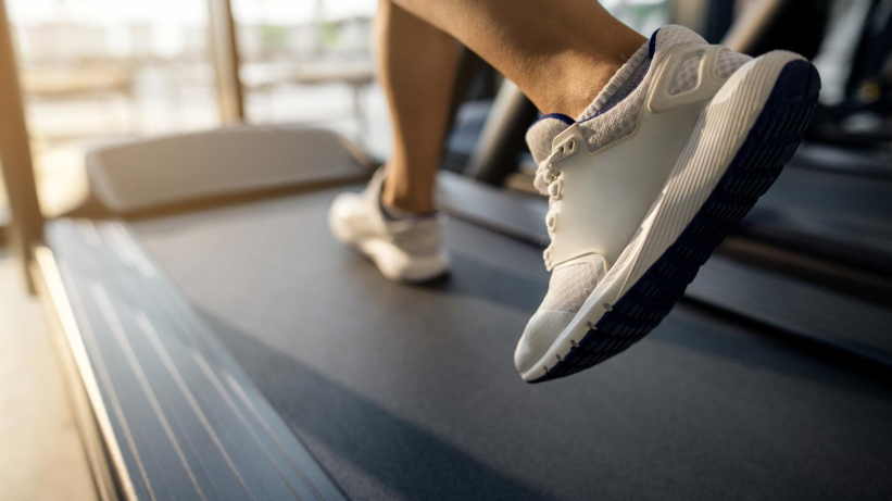 Laufen für Fitness Nahaufnahme eines Fußes in Laufschuhen auf einem Laufband, unscharfer Hintergrund eines Fitnessstudios