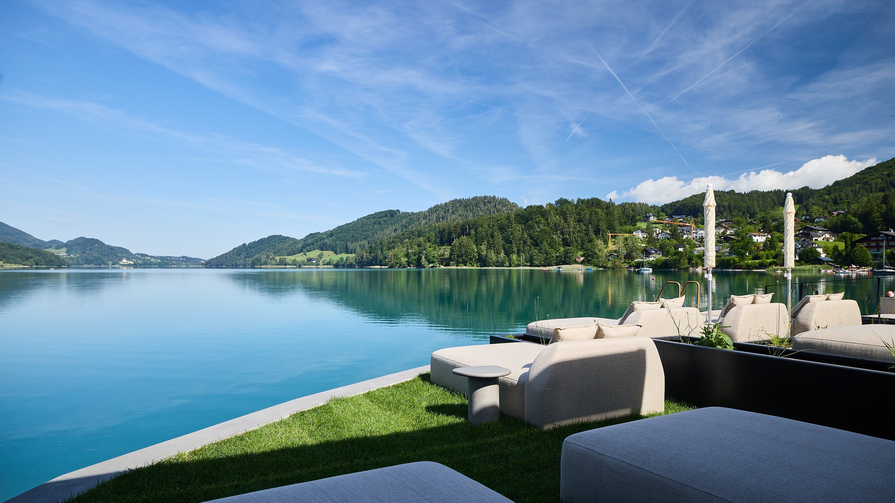 Erholsamer Blick auf den Fuschlsee Seeblick mit Freiluftbestuhlung und Berglandschaft im Hintergrund bei klarem Himmel